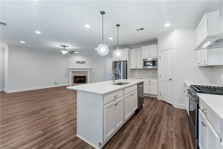 An open concept living area showcasing a well-appointed kitchen island and a cozy fireplace in the adjacent family room.