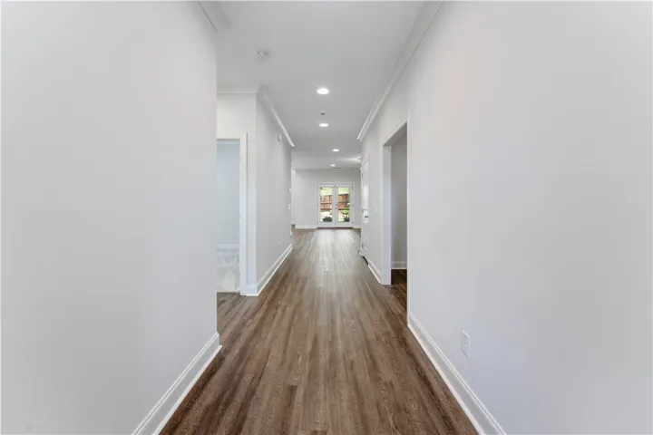 A long, inviting hallway with recessed lighting leads to French doors opening to the outdoors.