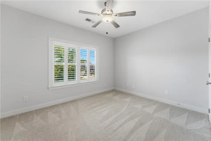 A quiet bedroom with a ceiling fan and carpeted floor provides a peaceful retreat.