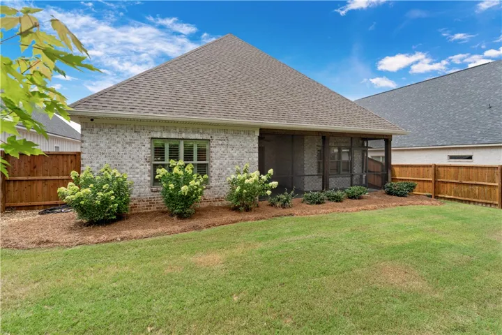 An inviting screened porch awaits, overlooking a manicured lawn and privacy fencing.