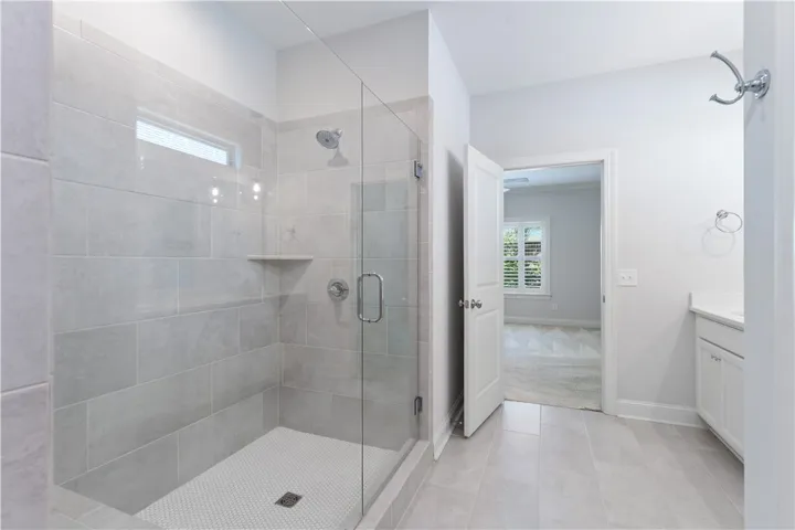 A well-lit, tiled shower with clear glass enclosure and built-in shelving offers a clean, functional bathing space.