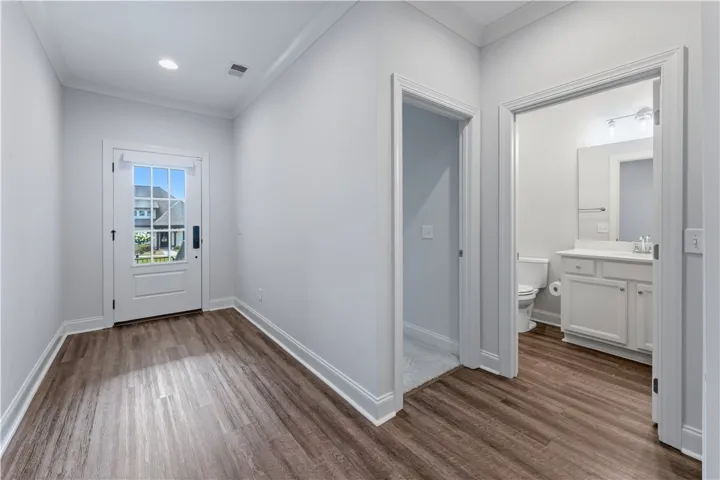 A welcoming entryway with rich wood flooring leads to a functional adjacent bathroom.