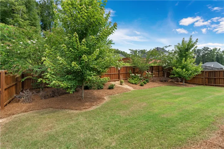A fully fenced backyard with well-maintained lawn and planted garden beds.