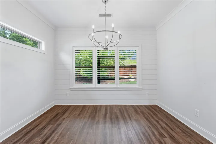 A refined dining space features durable wood flooring and elegant plantation shutters.