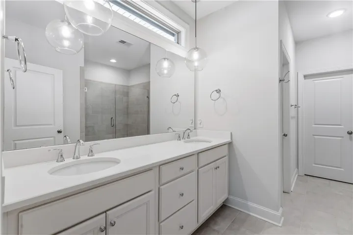 Double vanities with sleek countertops and stylish pendant lights elevate this serene primary bathroom.