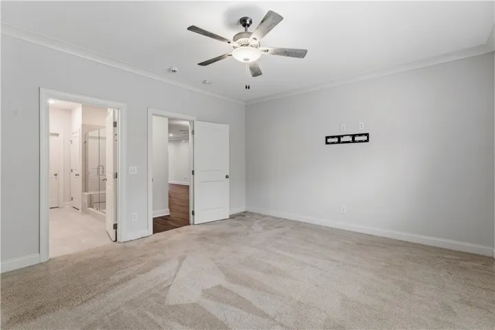 A quiet retreat with plush carpeting and modern ceiling fan, offering a seamless transition to an adjacent bath and additional living space.