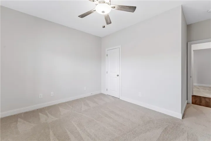 Well-lit room featuring soft carpeting and a convenient ceiling fan for comfort.
