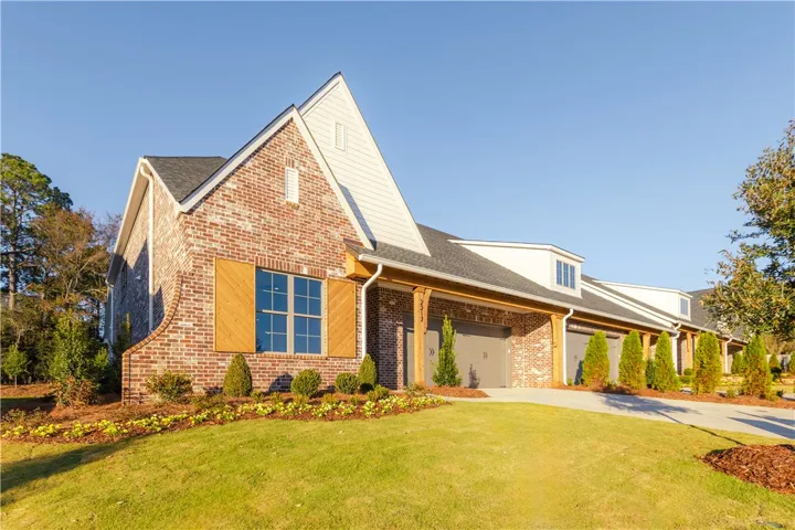 A charming brick exterior with wood shutters and lush landscaping creates appealing curb appeal.