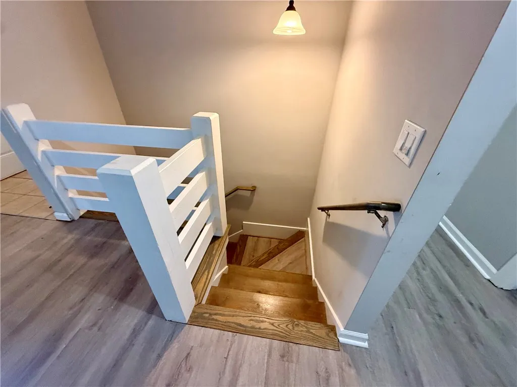 Natural wood stairs descend gracefully, complementing the lighter plank flooring above.
