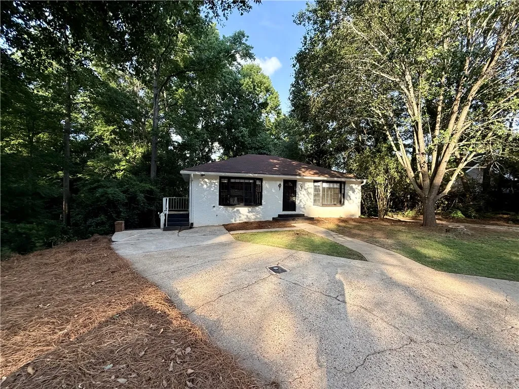 A well-maintained facade awaits, featuring a concrete driveway and mature shade trees.