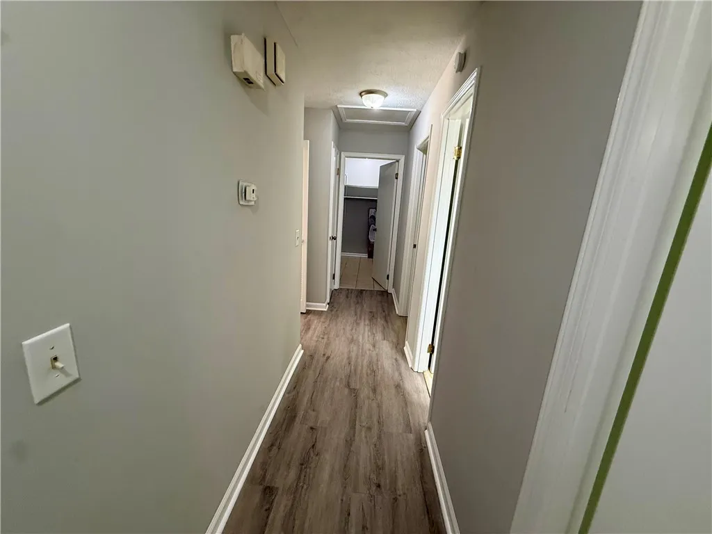A well-lit hallway with durable wood-look flooring connects various rooms within the residence.