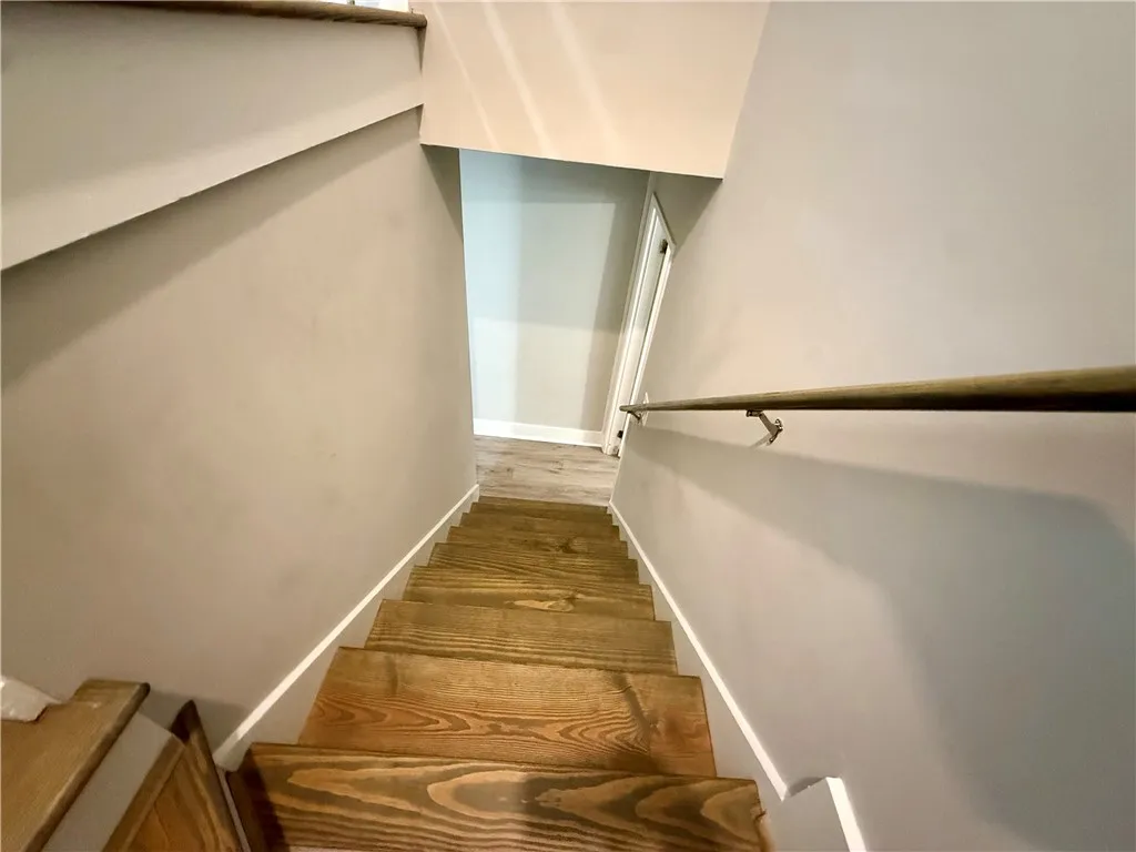 Natural wood stairs descend to a bright lower level.