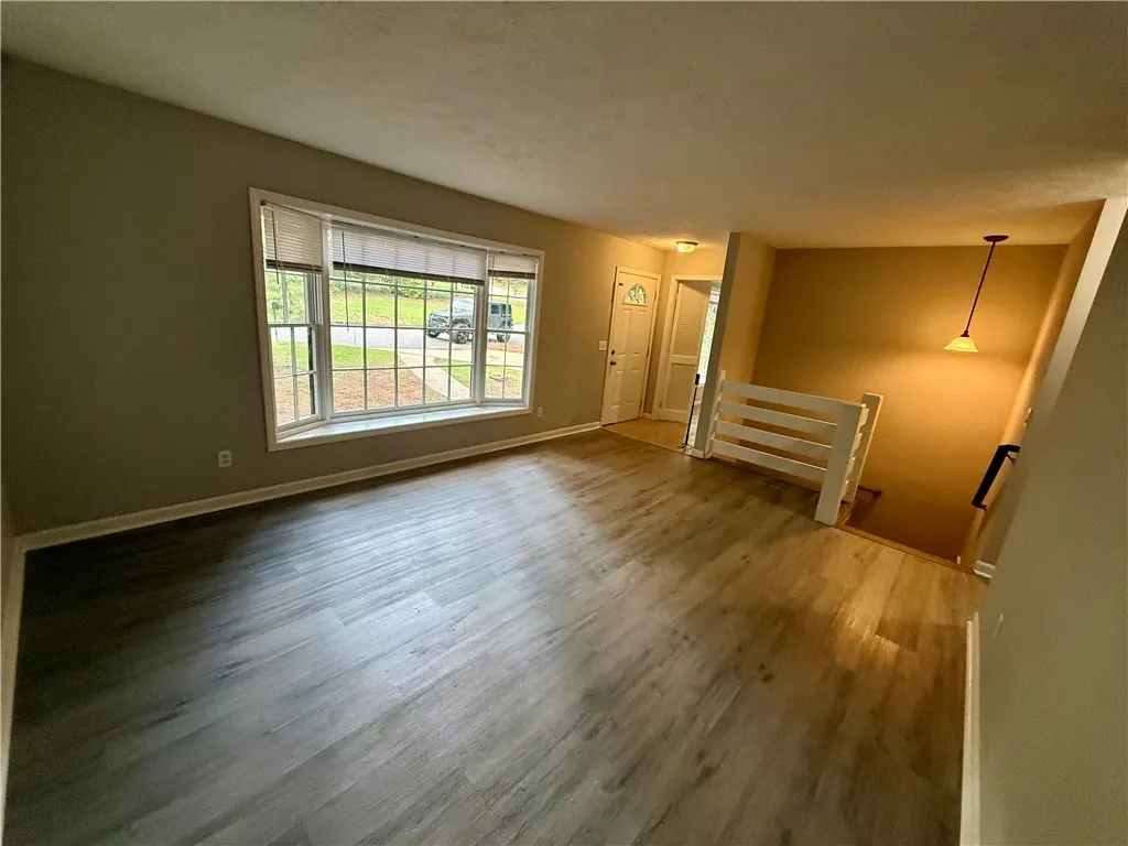A bay window naturally illuminates this spacious living area with resilient vinyl plank flooring.