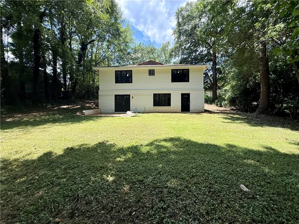 A private, verdant yard extends from a two-story residence nestled among mature trees.