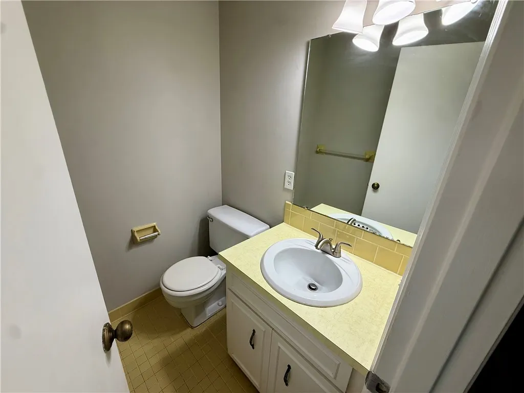 Functional full bathroom with a spacious vanity, large mirror, and tiled floors for practicality.