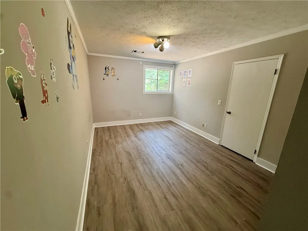 Well-lit room with wood-look flooring, ready for personalization.