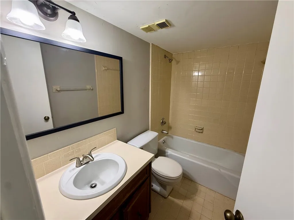 Functional bathroom featuring a single vanity and a combination tub/shower.
