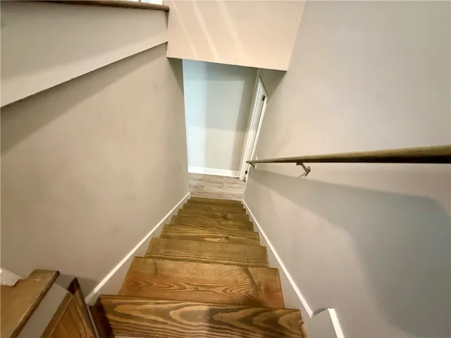 Natural wood stairs descend to a bright lower level.
