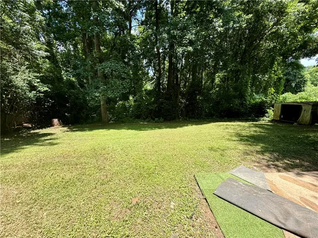 A verdant lawn meets a lush, wooded boundary, offering a secluded and spacious yard.