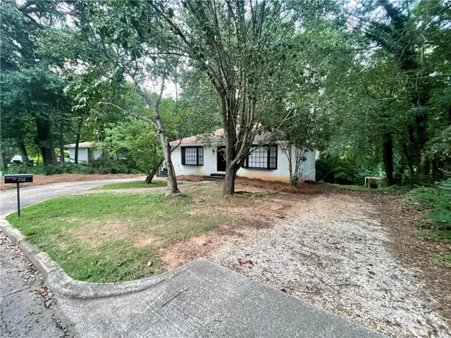A secluded dwelling nestled amidst verdant trees, featuring a generous gravel driveway leading to a private home.