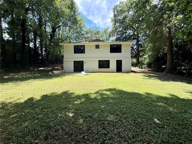A private, verdant yard extends from a two-story residence nestled among mature trees.