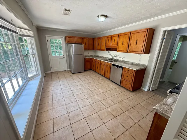 A well-equipped kitchen features ample cabinetry, durable tile flooring, and a large bay window inviting natural light.