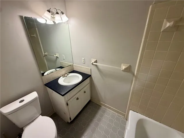 A well-lit lavatory space offering a vanity with counter space and an adjacent bathtub.