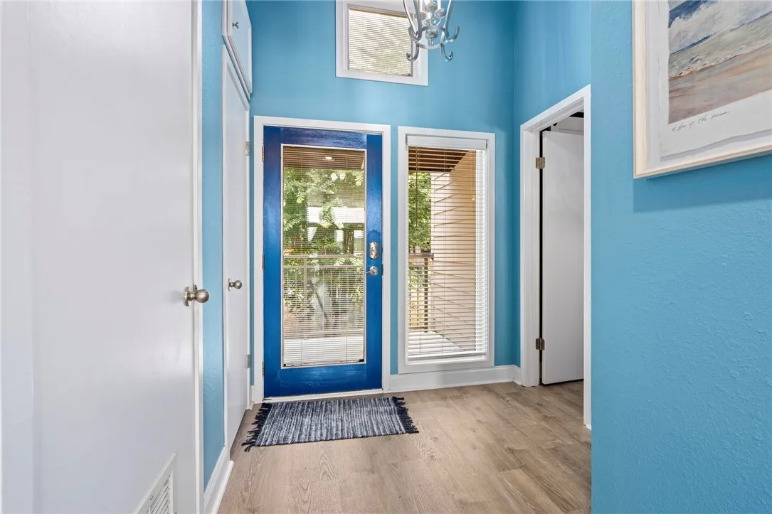 A vibrant blue door welcomes guests into a well-lit entry with warm-toned hardwood flooring.