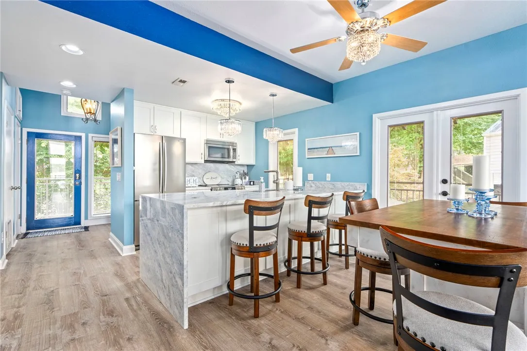 A vibrant kitchen features a breakfast bar, stainless steel appliances, and outdoor access through glass doors.