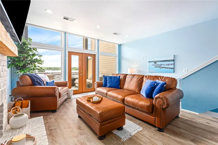 Sun-filled living area featuring rich leather furnishings and expansive lake views from the private balcony.