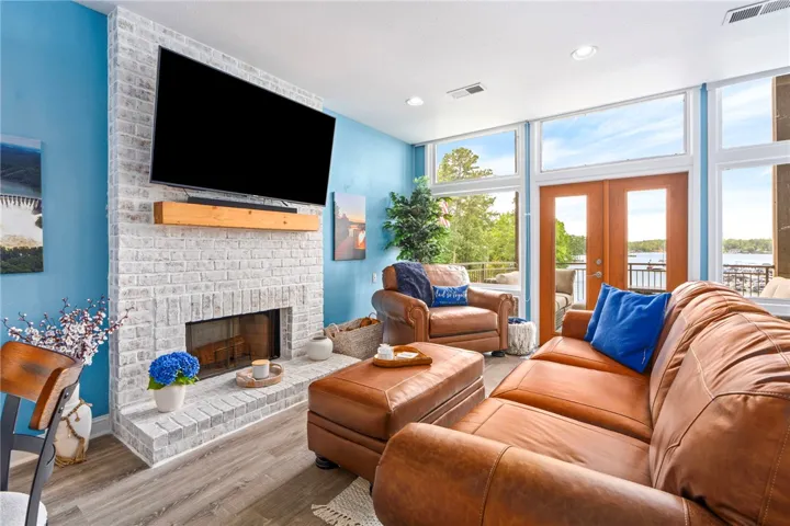 A well-lit living space with a stately fireplace offers panoramic views of the water.