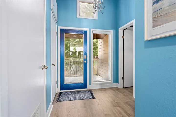 A vibrant blue door welcomes guests into a well-lit entry with warm-toned hardwood flooring.