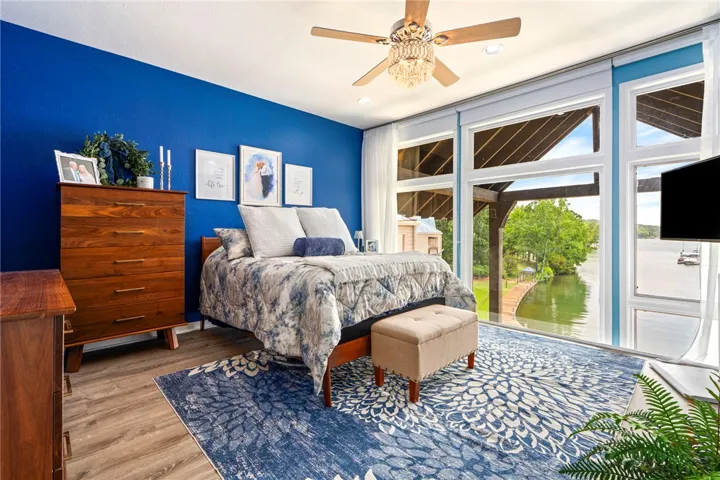Lakefront views and hardwood flooring elevate this primary bedroom to an oasis.