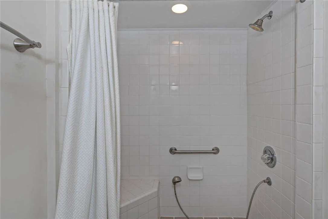 A well-lit shower features accessible seating and a convenient handheld sprayer.