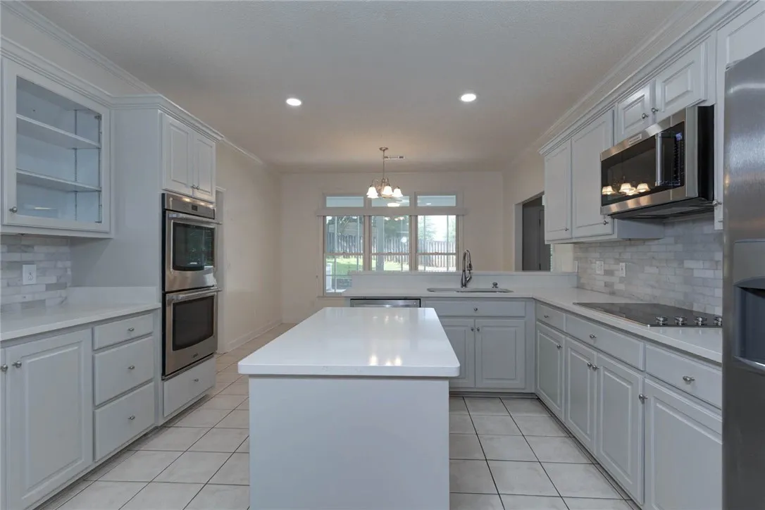 Gleaming white countertops and light cabinetry define this well-appointed kitchen.