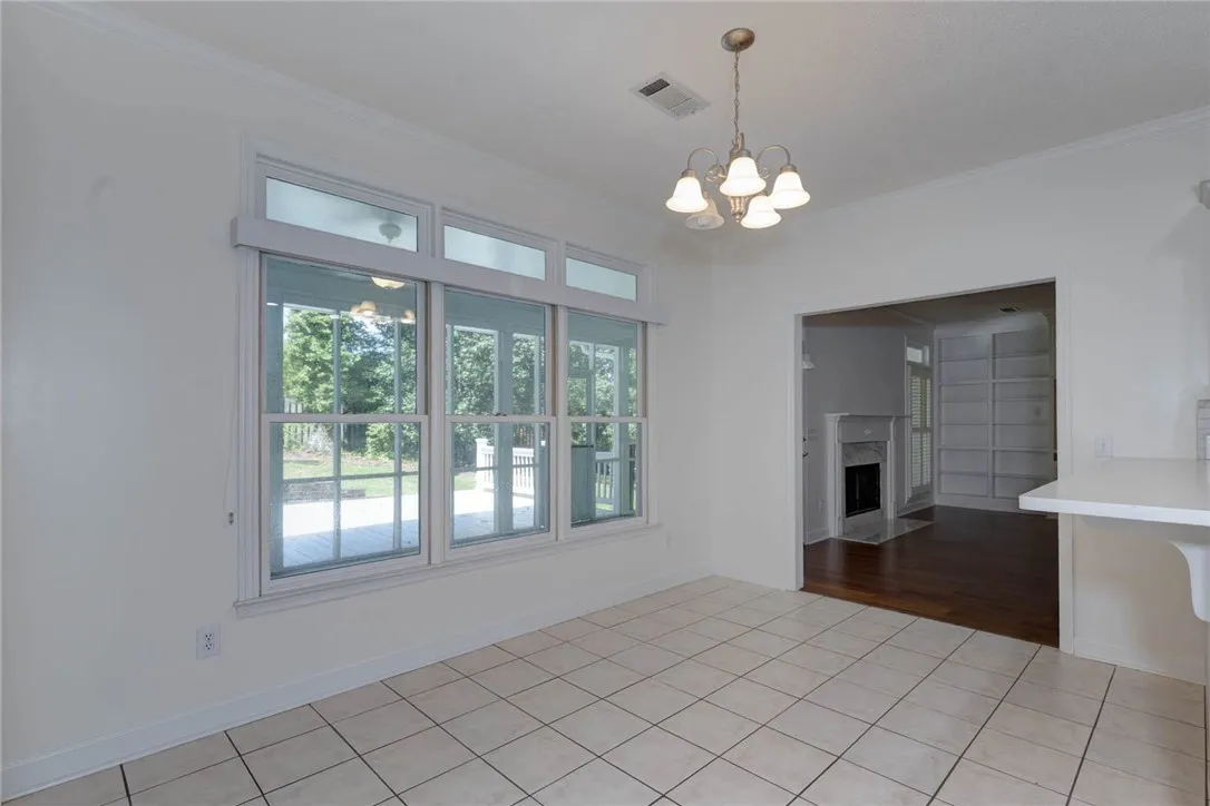 A well-lit dining area featuring a classic chandelier and large windows overlooking the patio.