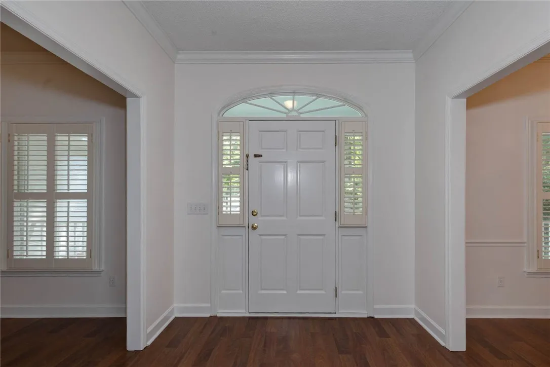 A welcoming entry features rich wood floors and an arched transom window, providing abundant natural light.