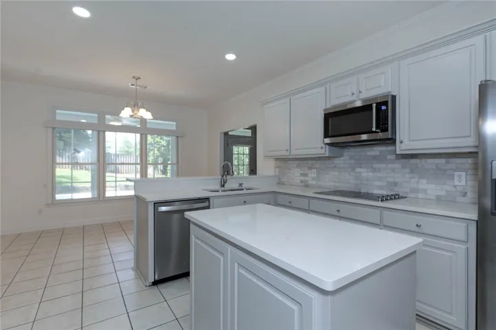A well-appointed kitchen showcasing a central island, modern appliances, and views to the yard beyond.