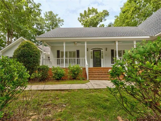 A welcoming front porch with brick steps and lush green landscaping creates inviting curb appeal.