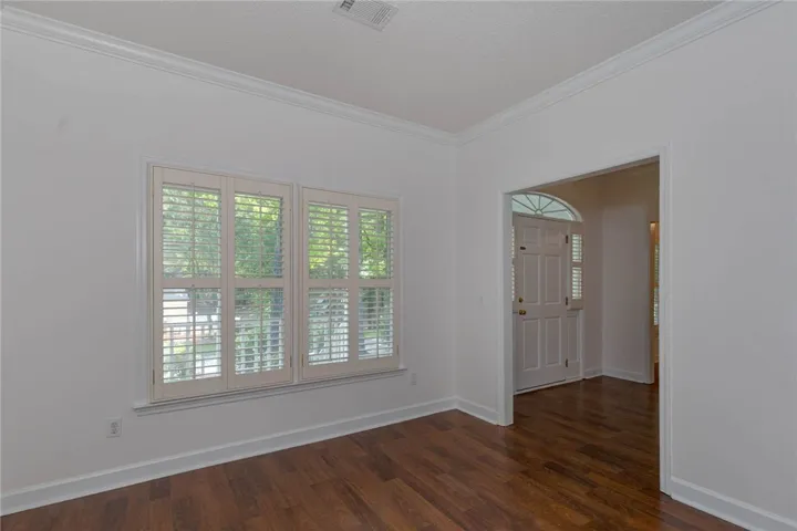 Rich hardwood flooring extends into a welcoming entryway, complemented by window treatments for privacy.