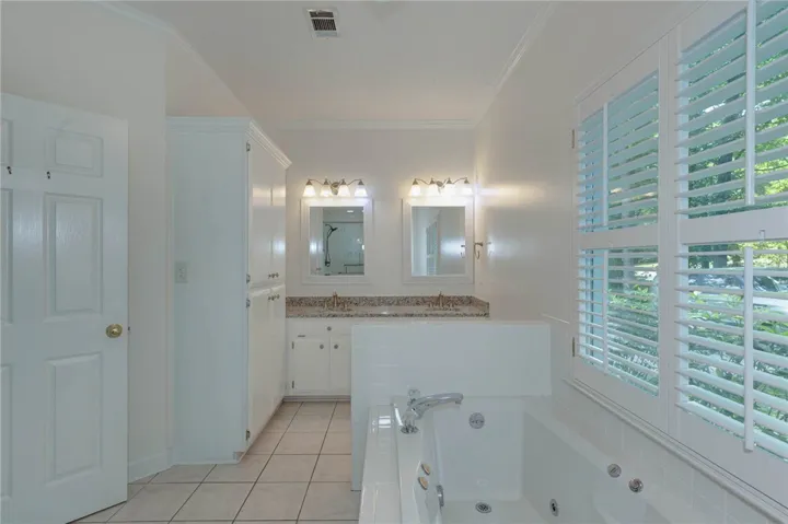 Indulge in a primary bathroom featuring a spacious soaking tub, dual vanities, and ample storage.