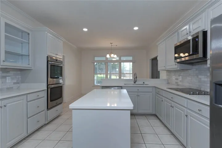Gleaming white countertops and light cabinetry define this well-appointed kitchen.