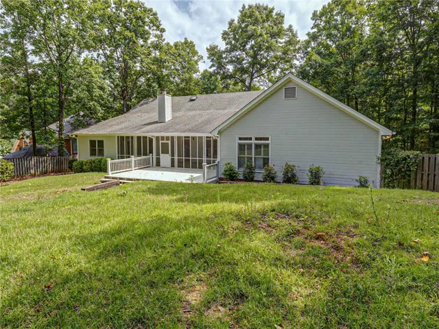 A tranquil backyard setting with a spacious screened porch and deck, ideal for outdoor leisure.