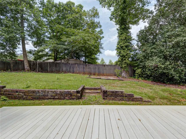 A spacious backyard with mature trees and a sturdy wooden fence offers privacy and room for recreation.