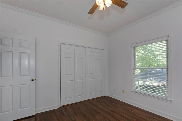 A quiet retreat with dark wood flooring, a window providing natural light, and a convenient closet.