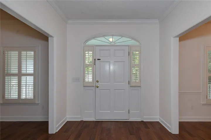 A welcoming entry features rich wood floors and an arched transom window, providing abundant natural light.