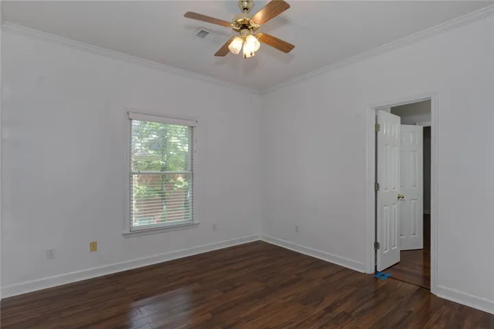 Rich hardwood-style flooring and a refreshing ceiling fan elevate this tranquil bedroom space.