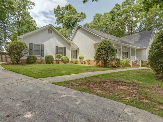 A classic exterior with a welcoming covered porch, mature trees, and a well-maintained lawn.