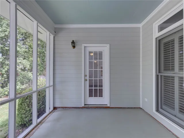 A well-lit screened porch offers serene outdoor living with views of surrounding trees.