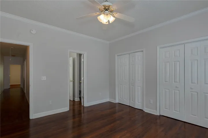 Rich hardwood floors complement a well-lit bedroom featuring practical bi-fold closets.